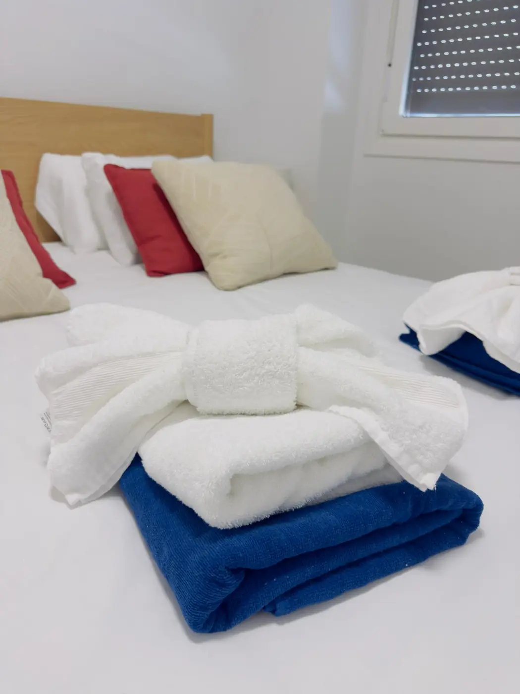 Dormitorio recién preparado con toallas dobladas sobre la cama