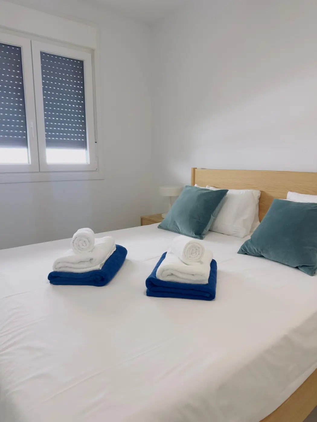 Dormitorio preparado con cojines azules y toallas dobladas